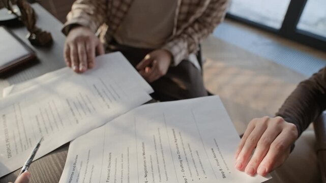 Close up of unrecognizable lawyer showing document to spouses during divorce consultation in office