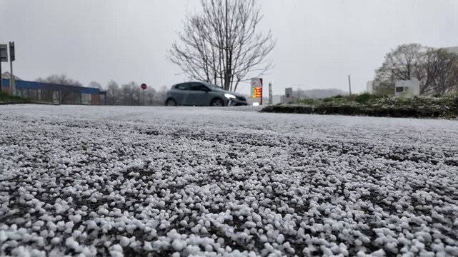 Gros plan sur des petits gr&ecirc;lons qui tombent sur le sol dans une ville. Boules de glace apr&egrave;s un orage de printemps. La gr&ecirc;le est une forme de pr&eacute;cipitation solide. Une temp&ecirc;te de gr&ecirc;le en France.