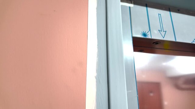 Ruban adh&eacute;sif imperm&eacute;able pos&eacute; sur un encadrement pendant les travaux d'am&eacute;nagement int&eacute;rieur, avec un mur peint en rose et un sol en lino gris. Pr&eacute;paration des travaux de r&eacute;novation.
