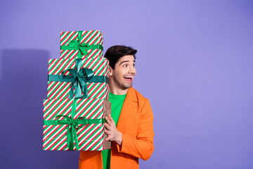 Naklejka premium Smiling man holding stack of wrapped Christmas presents in colorful outfit, excited holiday gift giving and festive celebration