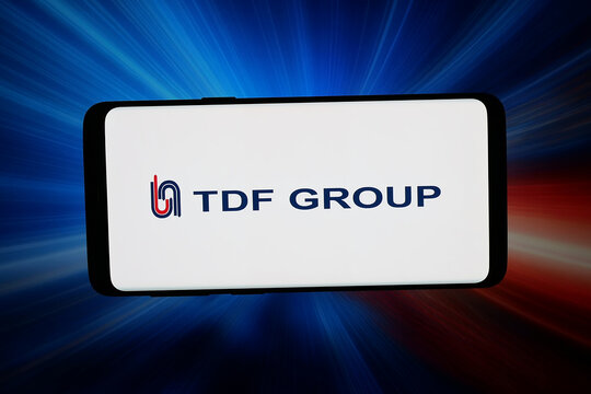 Stuttgart, Germany - 05-06-2026: In this photo illustration, the logo of company Tecnica de Fluidos S.L.U. (TDF Group) is displayed on a smartphone in front of abstract background on computer screen.