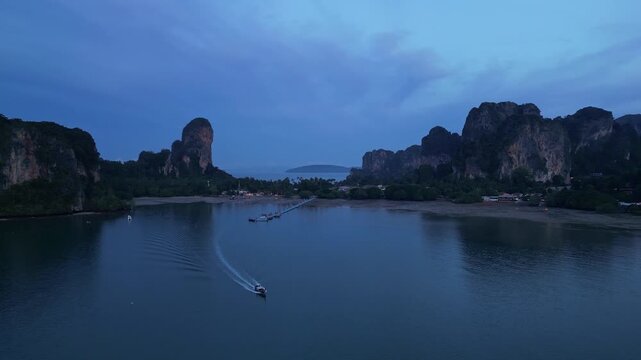 Krabi, Thailand : Aerial drone footage of traditional long tail boat leaves jetty in Railay east side in coastline of Krabi, Thailand surrounded by limestone cliff before sunrise