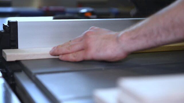 Circular table saw cutting wood in carpenter workshop close up. A running blade on a bench saw sawing trough the wooden log in the middle of a working space, close up footage. A sawing circle that cut