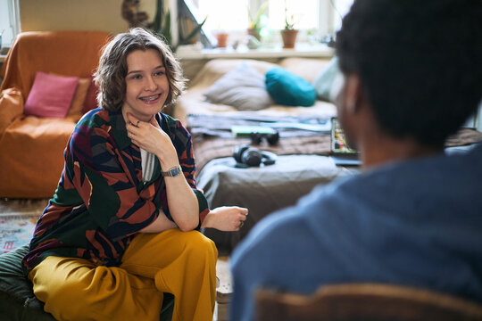 Teenage Caucasian girl smiling and speaking to African American male roommate while sharing house or apartment, discussing mental health support and communication. Useful for youth wellbeing campaigns