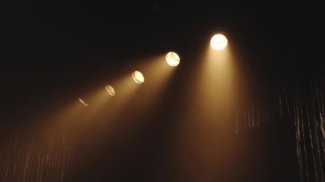 Warm spotlights shine through smoky darkness above a stage curtain, creating a cinematic atmosphere with copy space