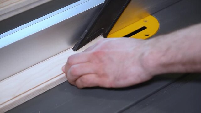 Circular table saw cutting wood in carpenter workshop close up. A running blade on a bench saw sawing trough the wooden log in the middle of a working space, close up footage. A sawing circle that cut