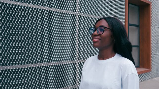 Woman explores urban area while looking at a metal fence on a sunny day