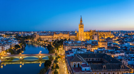 Fototapeta premium Panoramic aerial view of Seville, Spain at dusk, showcasing the Giralda tower and the Guadalquivir River.