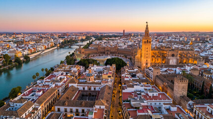 Obraz premium Panoramic aerial view of Seville, Spain, at sunset, showcasing the Guadalquivir River and the Giralda tower.