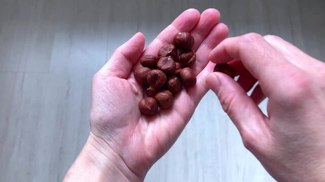 View from above. A woman's hand holds a hazelnut. A small snack. Natural nuts are a healthy and nutritious choice for quick energy replenishment throughout the day. Close-up