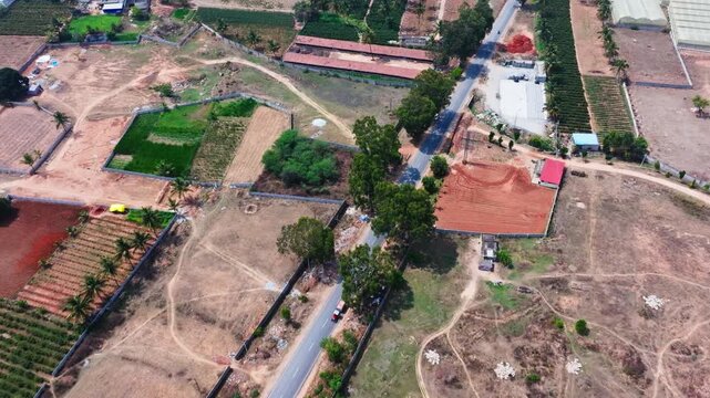 plantation rows with open dry fields, Agricultural tent houses, state highway 74, and SH 104 at nandi hills, kuduvathi village, karnataka, india. day time, push in shot, drone shot, 4k.