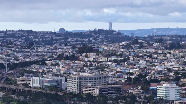 High altitude aerial drone footage over densely packed Broadmoor post-war tract homes in Daly City, California, revealing the San Francisco skyline through coastal marine layer haze.