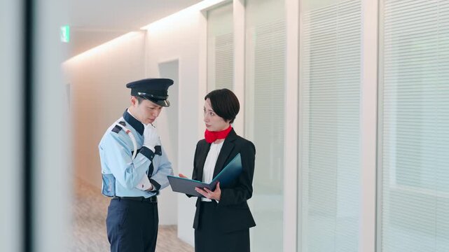 ロビーで会話する男性警備員と女性スタッフ