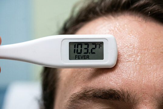 Checking high fever temperature on sweaty forehead with digital thermometer
