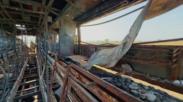 Interior of burned sleeper bus with twisted metal frames, charred passenger berths and torn panels showing severe fire destruction under daylight conditions!