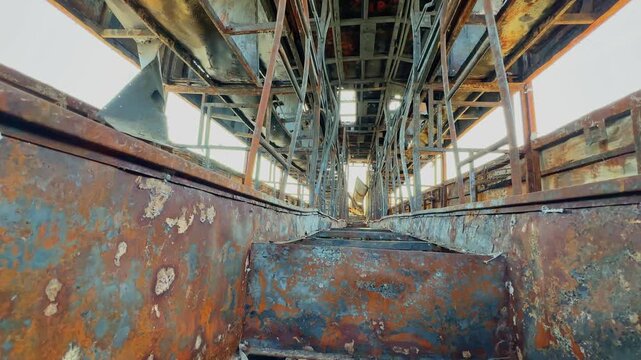 Low angle view inside charred sleeper bus showing rusted metal framework, exposed structure and severe fire damage throughout the passenger interior!