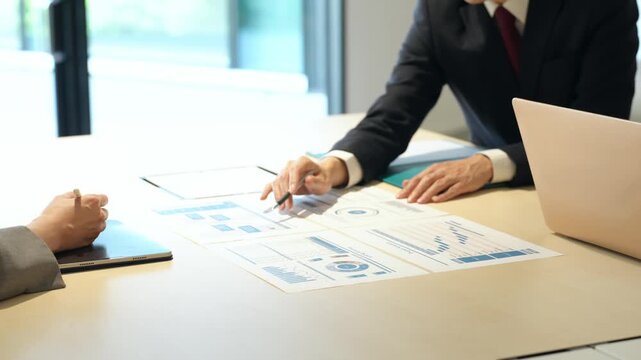 A group of business people having a meeting while looking at documents in the office.