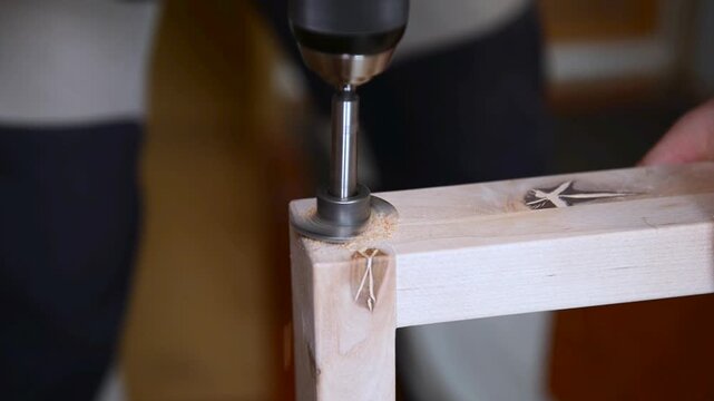 A man with works in his workshop. Profession carpenter. A man works with a tree. The carpenter takes drills holes wooden products in a bright workshop. Carpentry, craftsmanship, handwork concept.
