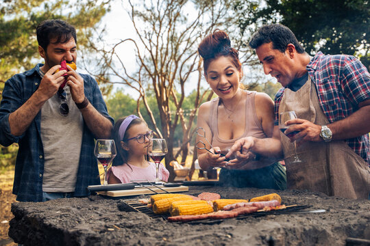 Friends and family enjoying outdoor barbecue together with grilled food and wine