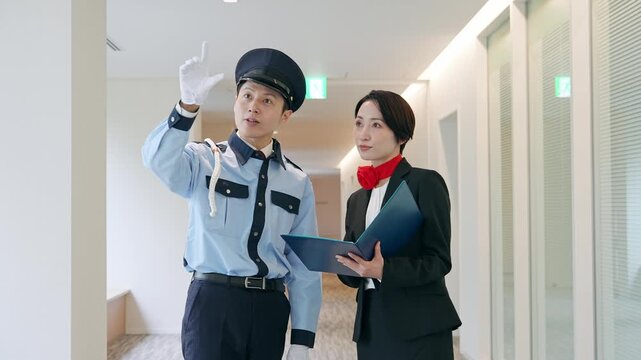 画面を見ながら会話する男性警備員と女性スタッフ
