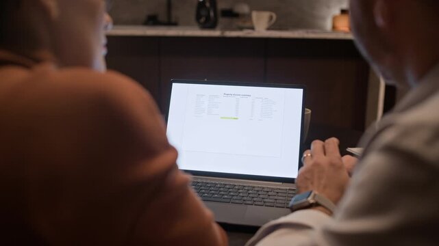 Over shoulder view of anonymous man and woman chatting and looking at laptop screen while discussing divorce document