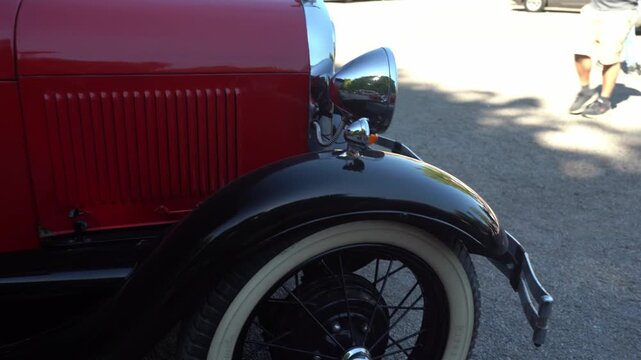 Berlin, Germany - May 2, 2026: Close-up left-to-right pan across the fender, chrome headlight and whitewall tire of a vintage car during Oldtimer Open Air at Zitadelle Spandau.