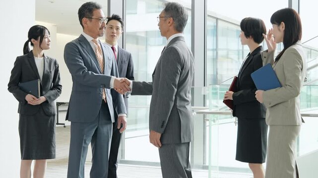 オフィスで握手するビジネスパーソンのグループ