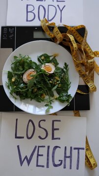 Vertical screen healthy salad on kitchen scale between Ideal Body and Lose Weight signs symbolizing eating disorder pressure calorie obsession and toxic body standards