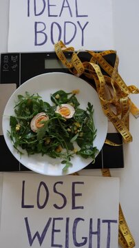 Vertical screen healthy salad on scales with ideal body and lose weight signs reflects pressure of diet culture and obsession with perfect summer body goals