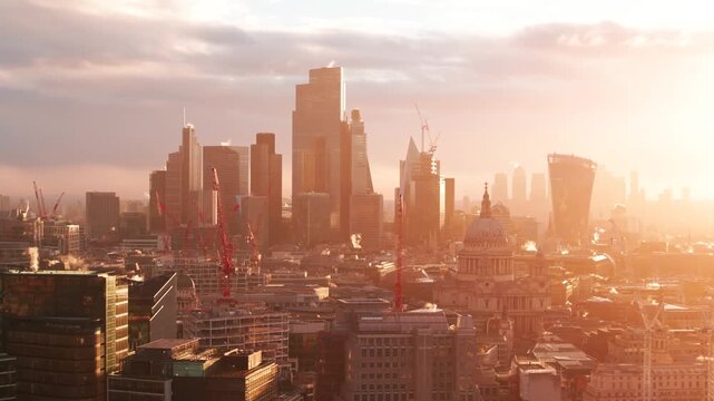 Aerial drone footage of London skyline with skyscrapers and St Pauls Cathedral at sunrise.