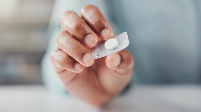 Close up of hand holding single white pill in blister pack for health and medicine concept