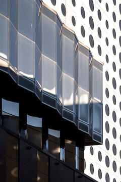 Curved facade with windows and an abstract pattern across the building exterior, where reflection shapes architecture and close detail