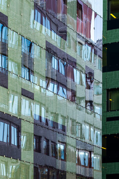 Reflected facade with windows and glass creating an abstract urban texture across a building exterior with layered pattern and distorted detail