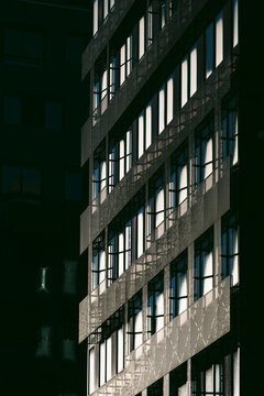 Shadow facade with windows on a dark building exterior, using urban architecture contrast and narrow detail across the angled surface