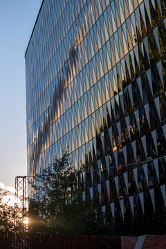 Glass facade on a modern building with windows catching reflection and evening sunlight across urban architecture and a layered exterior edge