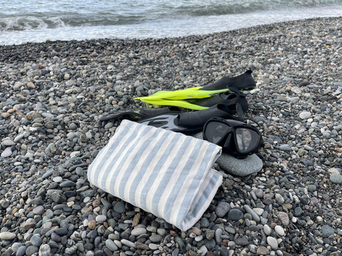 flippers and mask for diving near the towel on the beach