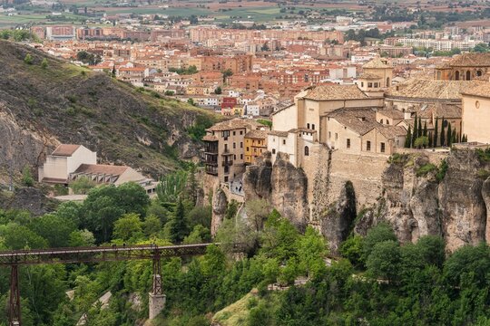 View of Cuenca cliffside old town with Hanging Houses and iron bridge surrounded by green landscape in Castilla La Mancha Spain