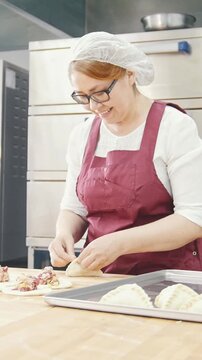 Adult kind smiling woman bakes and forming cakes in the bakery