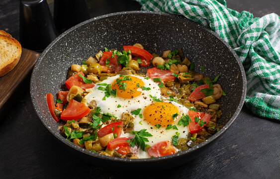 Rustic Skillet Eggs with Tomatoes and Herbs on Dark Background.