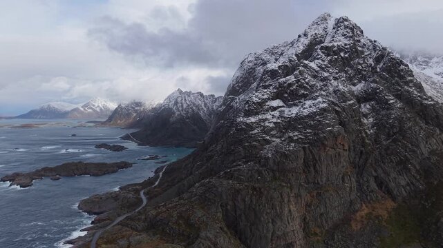 Mountains stand tall over the water in a cold place with snow on the peaks