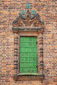 Green window framed by weathered brickwork