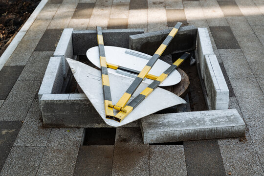 Traffic signs stored. Maintenance crew temporarily organizing safety equipment outdoors. Sunlit striped poles positioned in concrete frame during maintenance pause and safety setup