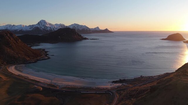 Sunrise over a beach with mountains in the background near a calm sea in Norway