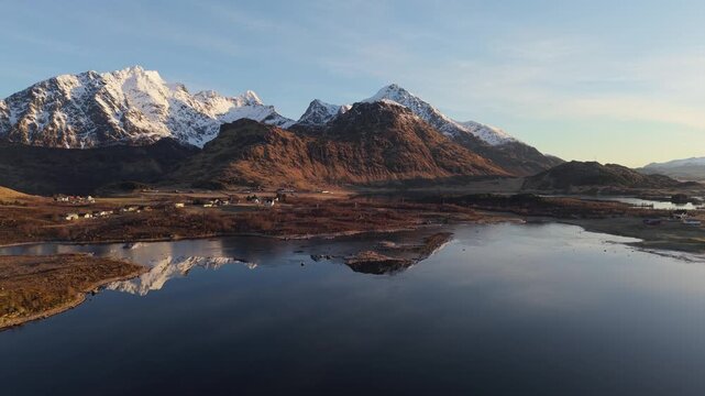Mountains and water reflect during sunset in a landscape with snow capped peaks