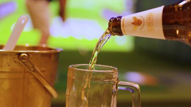Pouring Cold Beer into a Glass Mug at an Indoor Golf Simulator