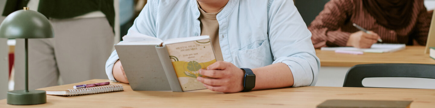Header of migrant student reading textbook during classroom lesson, studying language integration and academic progress. Useful for education access, inclusion, resettlement campaigns
