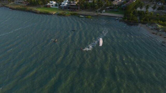 Kitesurfer rides fast across shallow lagoon in Ilha do Guajiru Itarema Ceara Brazil surrounded by coconut coastline tropical estuary and steady trade wind conditions, drone pullback wide shot