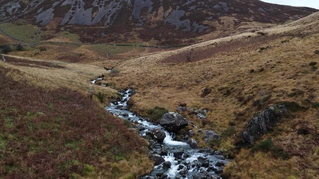 Aerial view flying over a mountain stream in a valley