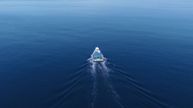 Aerial view of a boat cruising on the deep blue sea with a white wake in Vashafaru, Haa Alif Atoll, Maldives.