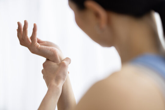 Asian Woman in Yoga Wear Touching Wrist with Painful Expression